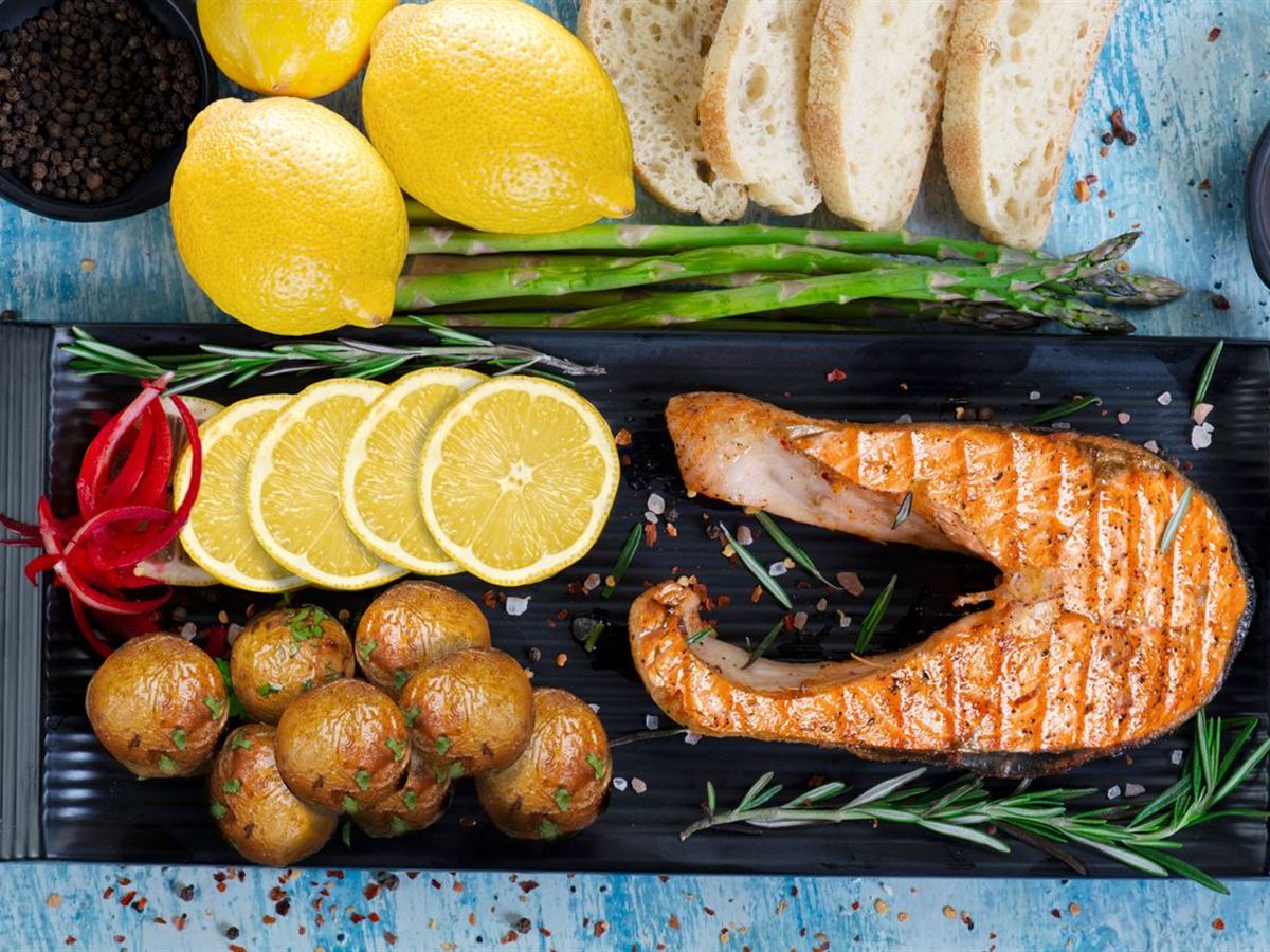 Grilled salmon with lemon, potatoes and asparagus on a rustic table